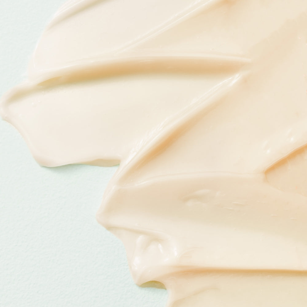 Close-up of smooth, beige cream on a light blue background