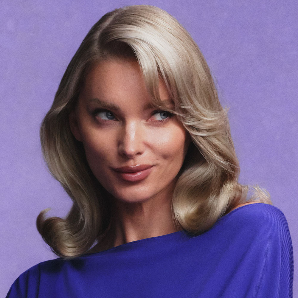 Woman with blonde hair wearing a blue top against a purple background